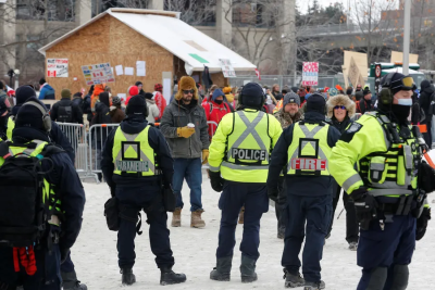 Police watch over as truckers and their supporters continue to protest against the COVID-19 vaccine mandates, in Ottawa, on Feb. 6.